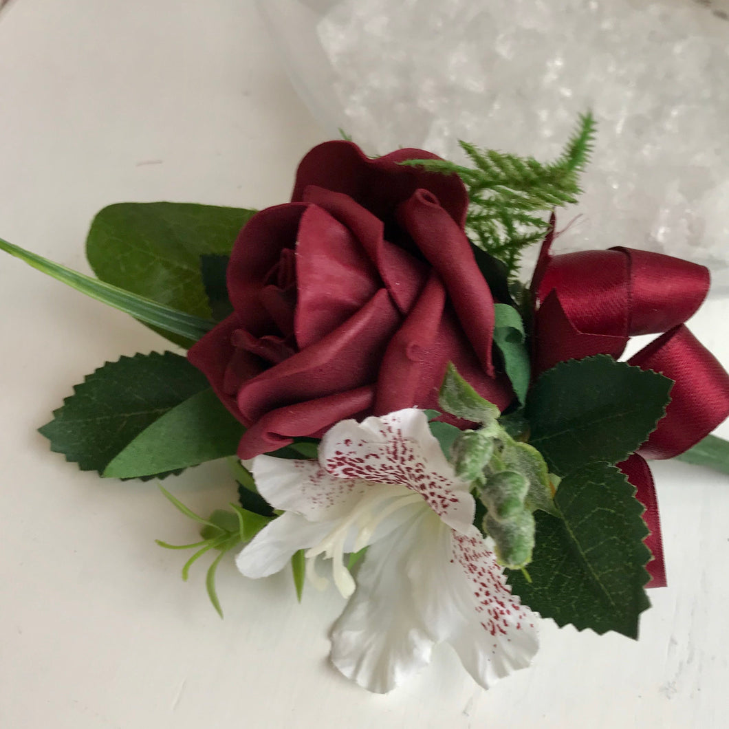 A wedding corsage featuring a bugundy foam roses and hydrangea
