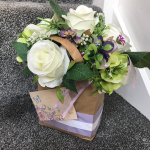 A flower arrangement of artificial roses in a gift bag
