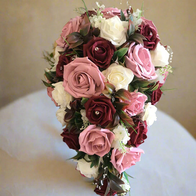 A teardrop bouquet of artificial burgundy, ivory & pink roses, crystals & pearls