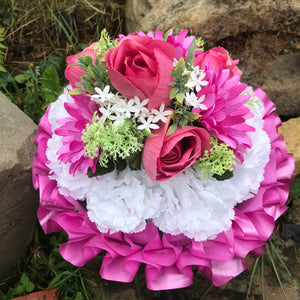 A based funeral posy featuring artificial flowers in shades of pink and white