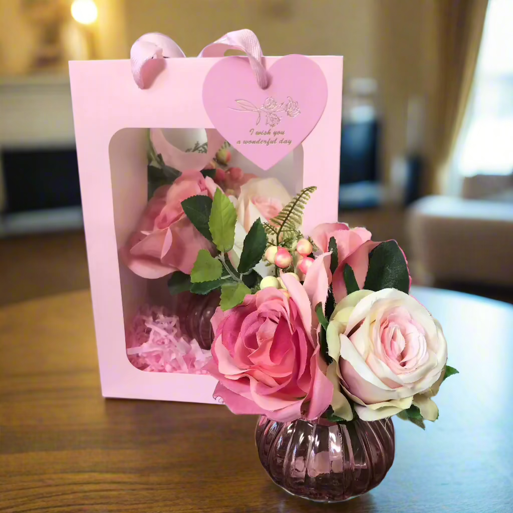 A small posy arrangement of pink silk roses in presention giftbag