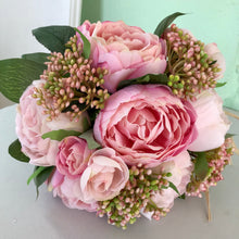 A brides bouquet featuring pink peonies