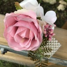 A wrist corsage featuring a dusky pink artificial silk rose