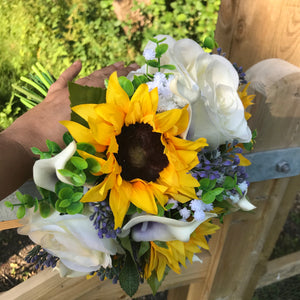 A wedding bouquet featuring calla lilies, roses & sunflowers