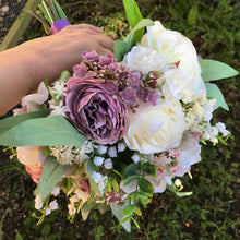 A wedding bouquet of artificial ivory roses, lily of the valley and foliage