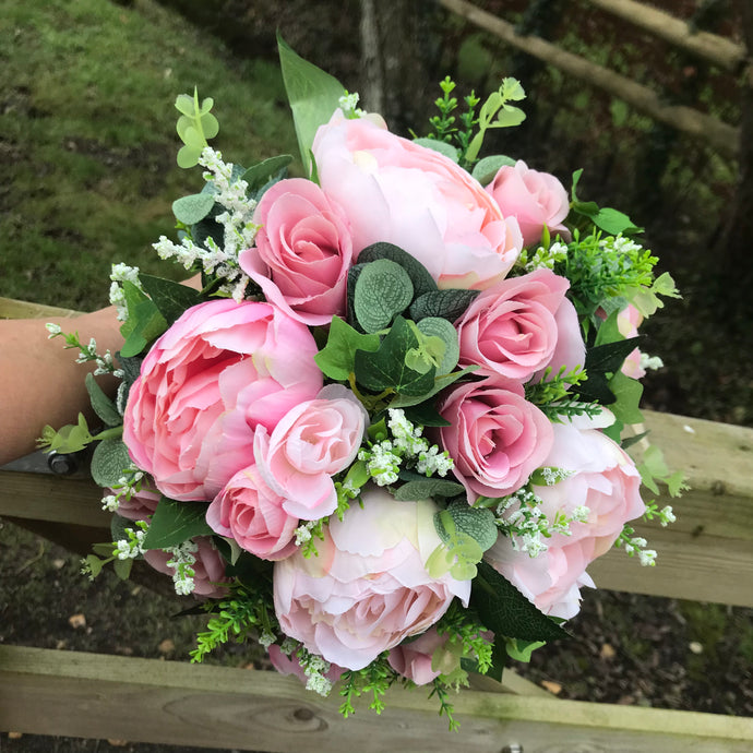 A wedding bouquet featuring pink peonies and foliage