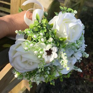 A brides wedding bouquet of artificial silk ivory roses and daisies