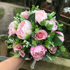 A wedding bouquet featuring pink peonies and foliage
