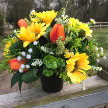 a grave side artificial silk flower arrangement in shades of yellow and orange
