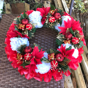 a memorial christmas wreath featuring baubles, cones and poinsettia