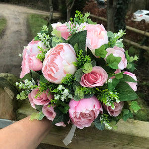 A wedding bouquet featuring pink peonies and foliage