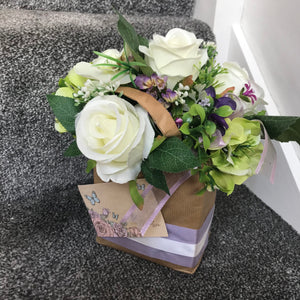 A flower arrangement of artificial roses in a gift bag