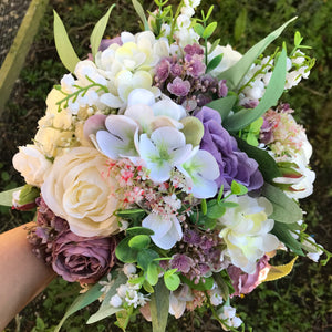 A wedding bouquet of artificial ivory roses, lily of the valley and foliage