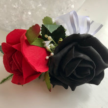 A flower corsage featuring black and red foam roses