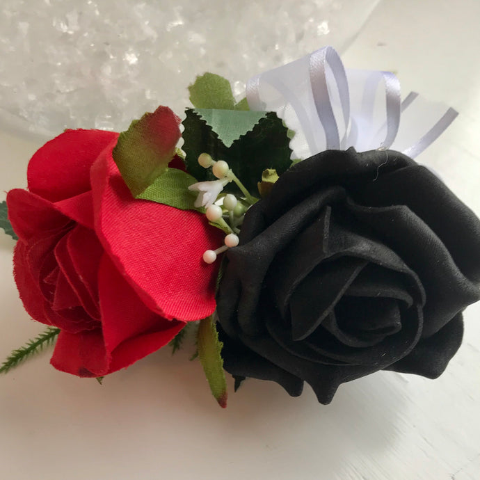 A flower corsage featuring black and red foam roses