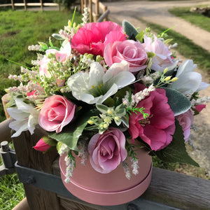 a large artificial flower arrangement in pearlescent hat box