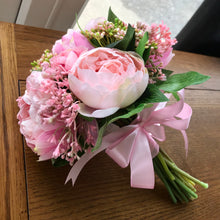 A brides bouquet featuring pink peonies