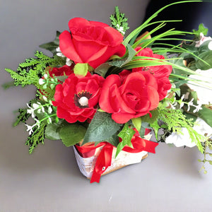 flower arrangement of artificial red anenomies & ivy in a gift bag