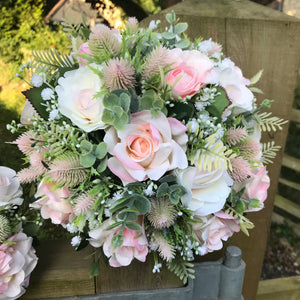 A bouquet collection of gypsophila and artificial pink roses, foliage and thistles