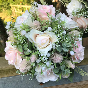 A bouquet collection of gypsophila and artificial pink roses, foliage and thistles