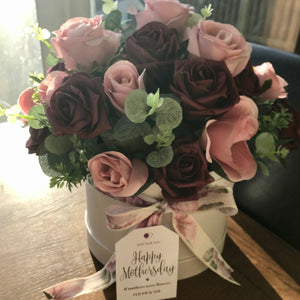 a flower arrangement of artificial roses in hat box