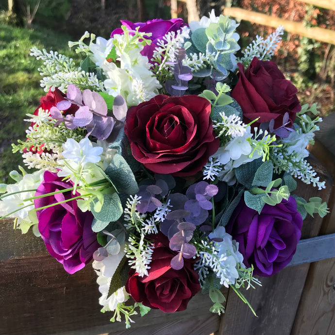 A wedding bouquet of artificial ivory & purple flowers