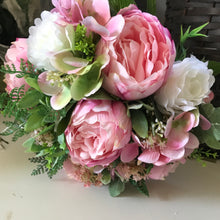 A brides bouquet of artificial pink peonies and ivory roses