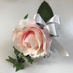 A buttonhole featuring a blush pink silk rose
