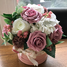 A large flower arrangement in pink hat box