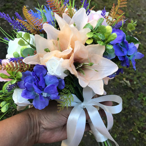 A bridal bouquet of artificial ivory, peach and purple flowers