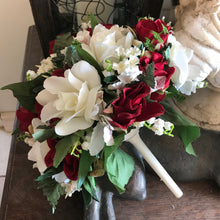A brides bouquet featuring red and ivory artificial flowers
