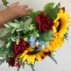 An artificial wedding bouquet collection of red roses, forget me nots and sunflowers