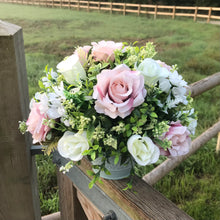 a flower centrepiece of pink and ivory roses and foliage