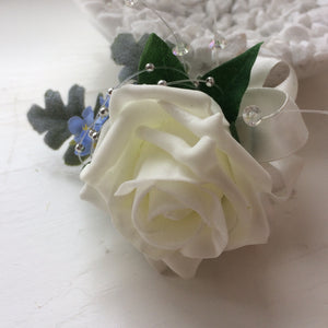 An artificial wedding buttonhole featuring an ivory rose & blue forgetmenots