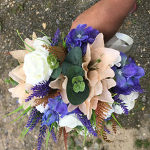 A bridal bouquet of artificial ivory, peach and purple flowers