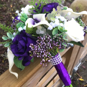 A wedding bouquet of ivory and purple silk flowers