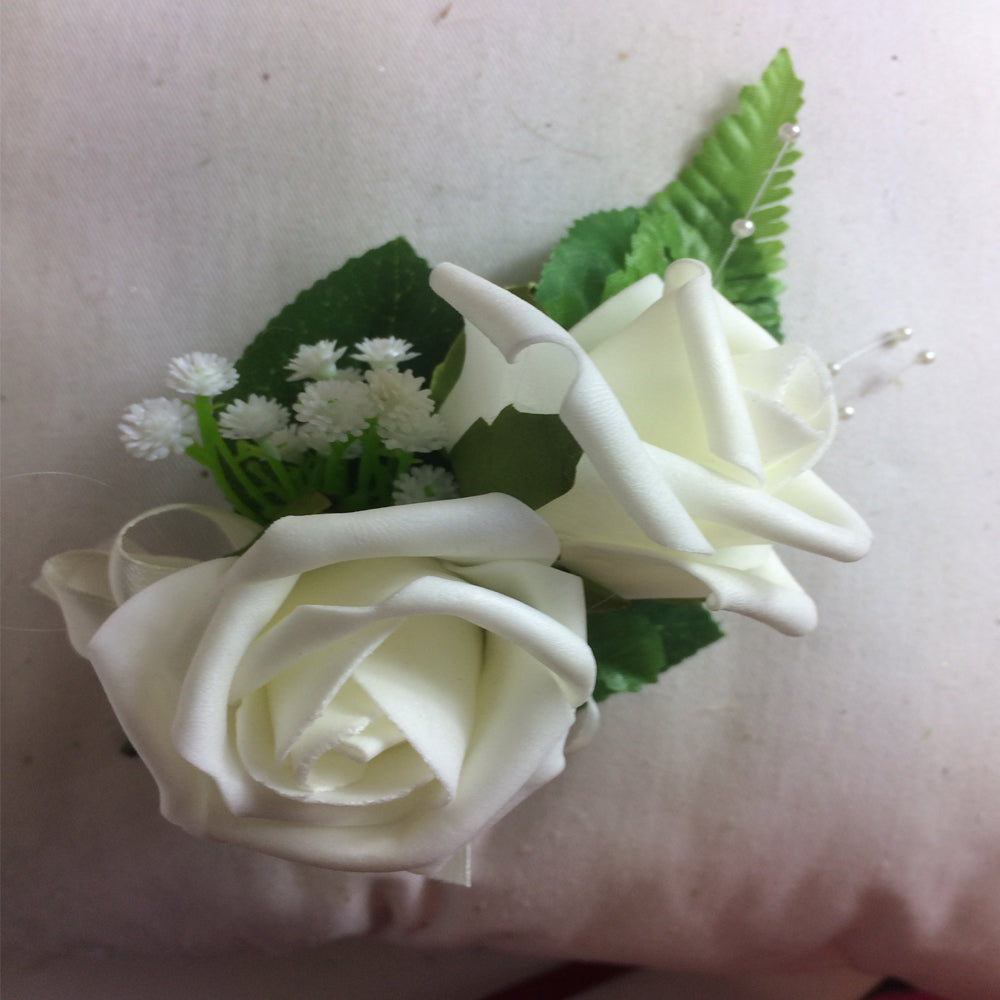 an artificial corsage featuring ivory foam roses